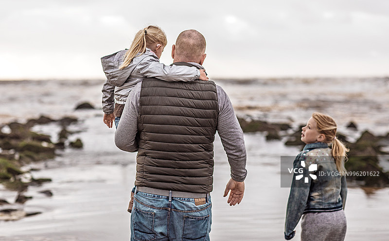 单亲父亲和女儿们在冬季海滩上玩家庭游戏图片素材
