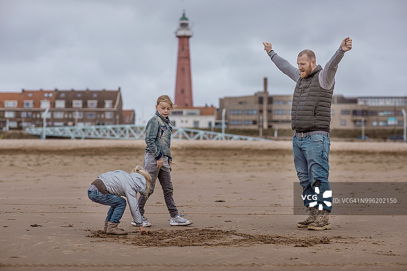 单亲父亲和女儿们在冬季海滩上玩家庭游戏图片素材