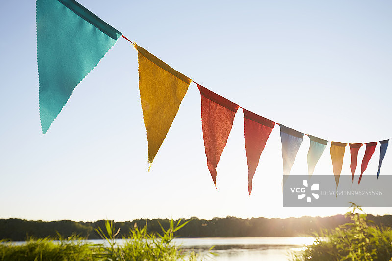 湖边天空背景上用于聚会装饰的彩色三角旗图片素材