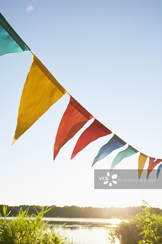 湖边天空背景上用于聚会装饰的彩色三角旗图片素材