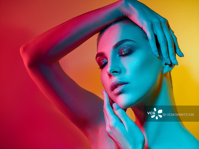 在演播室中以彩色灯光摆姿势的高级时装模特图片素材