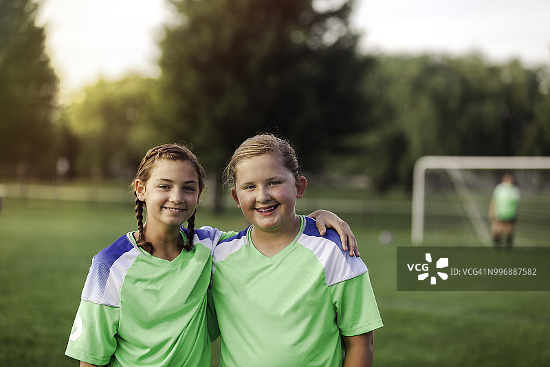 两名女足队友在足球场上互相搂着肩膀图片素材