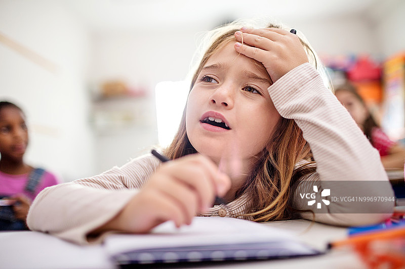 疲惫的女学生在教室里手托着头图片素材