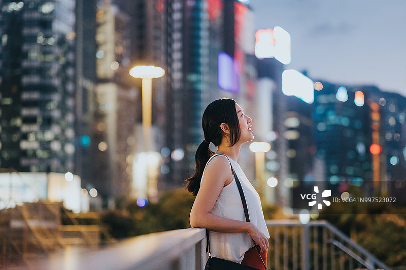 在城市里欣赏壮观日落的美丽年轻女人图片素材