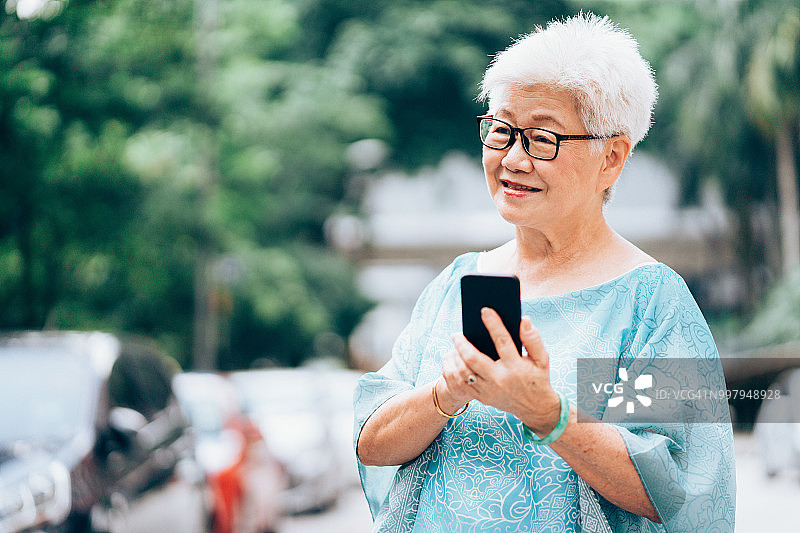 在城市中使用智能手机的年长亚洲女性图片素材