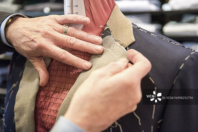 裁缝在人台上准备定制西装外套，手部特写图片素材