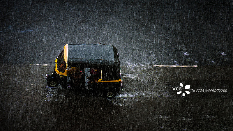 孟买道路上的一辆自动人力车，大雨倾盆图片素材