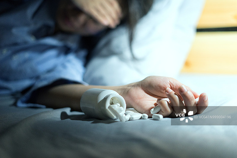 亚洲女人晚上在床上感到不舒服并手持药片图片素材