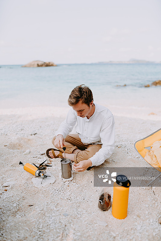 男人在冲绳热带海滩露营的早晨做咖啡，日本图片素材