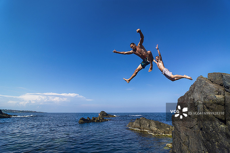 两个年轻人从悬崖跳入海中图片素材