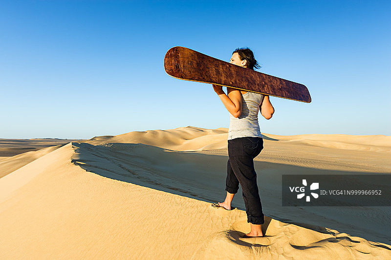 年轻女子在非洲撒哈拉沙漠滑沙图片素材