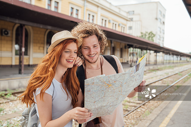 年轻夫妇站在火车站阅读地图图片素材