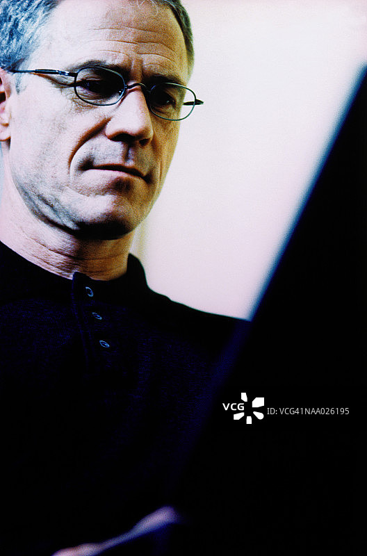 表情严肃地看着笔记本电脑的中年男人特写图片素材