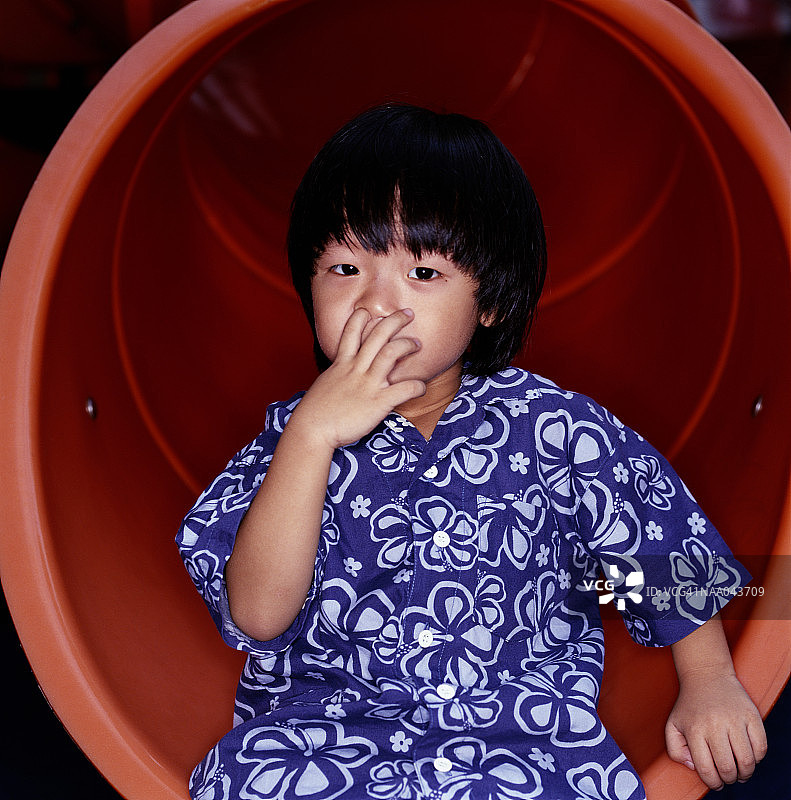 男童坐滑梯抠鼻子肖像图片素材