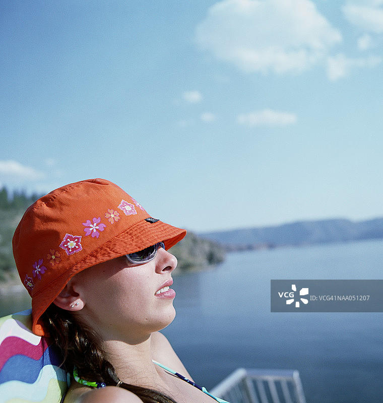 年轻女人在湖边晒太阳，侧面轮廓图片素材