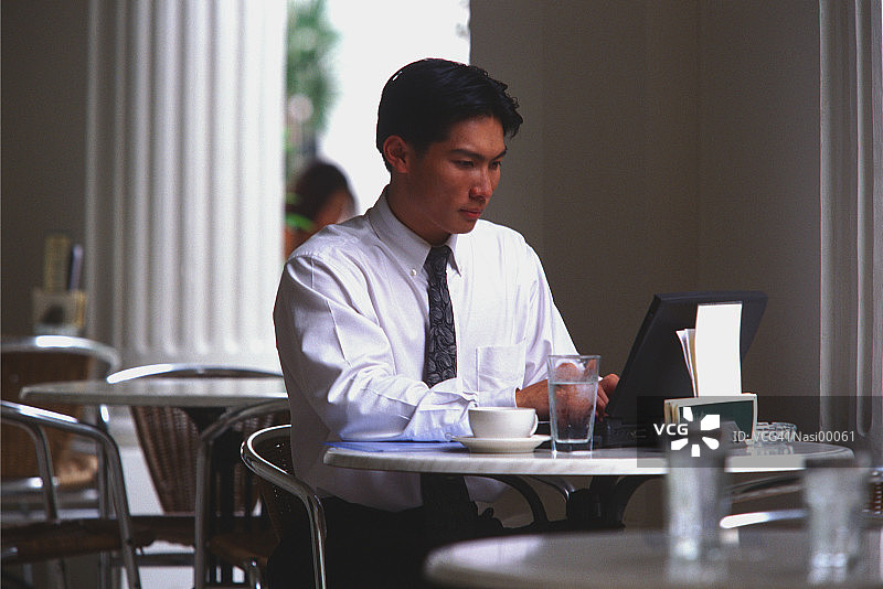 在咖啡馆用笔记本电脑工作的男人图片素材