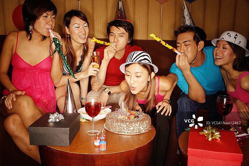 年轻人们戴着派对帽，吹着响亮的玩具庆祝图片素材