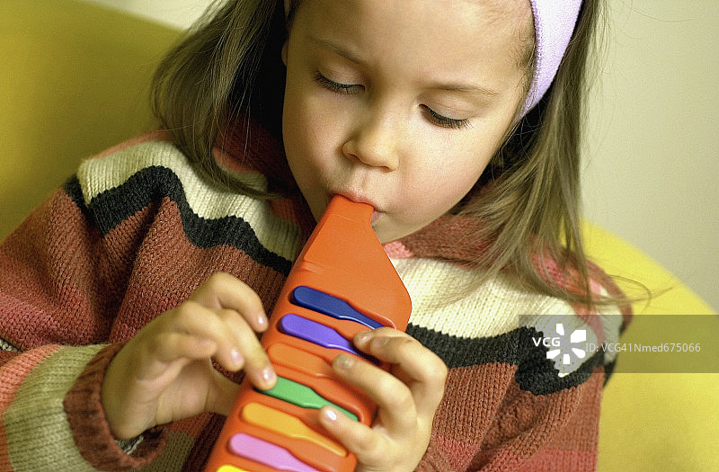 小女孩吹儿童玩具乐器特写图片素材