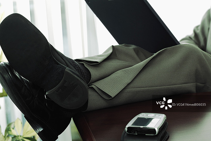 脚放在桌子上的商人使用笔记本电脑图片素材