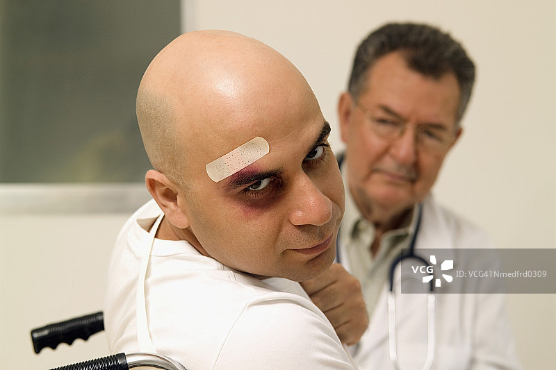 头部缠着绷带的光头男人与医生近距离选择性聚焦图片素材