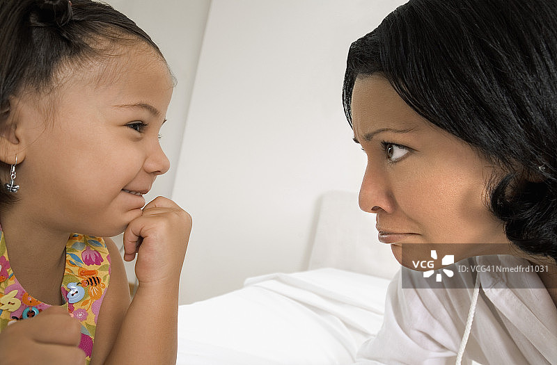 微笑的女孩和嘟嘴的女人互相看着，特写图片素材