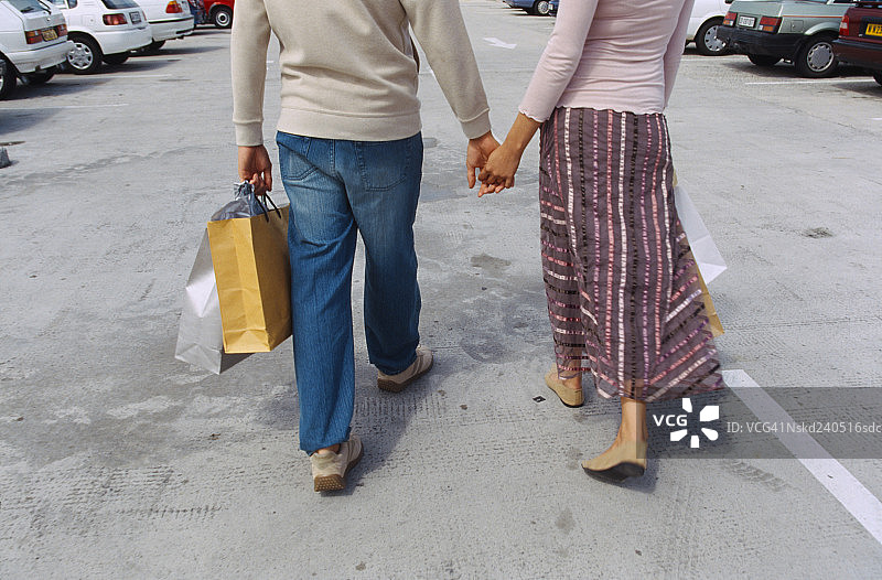 提着购物袋走在街上的年轻情侣背影图片素材