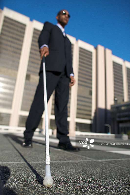 低角度拍摄的盲人拄着白色手杖行走图片素材