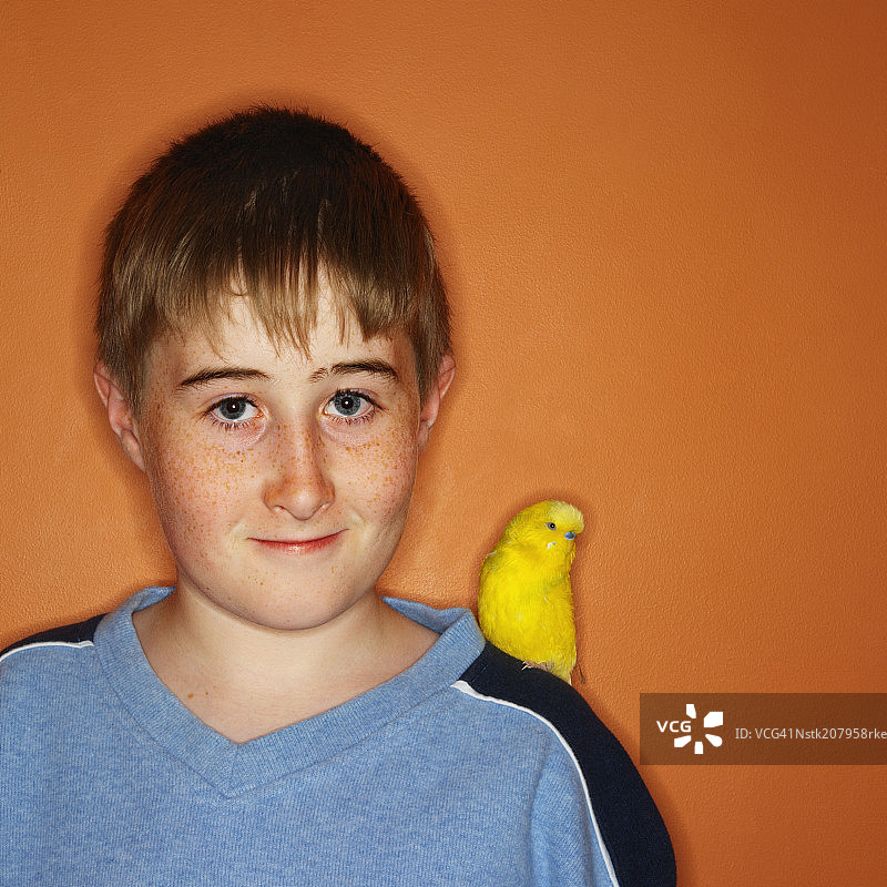 肩扛鹦鹉的青少年男孩肖像图片素材