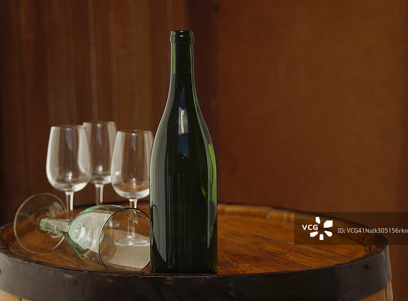 葡萄酒瓶与酒杯置于木桶上图片素材