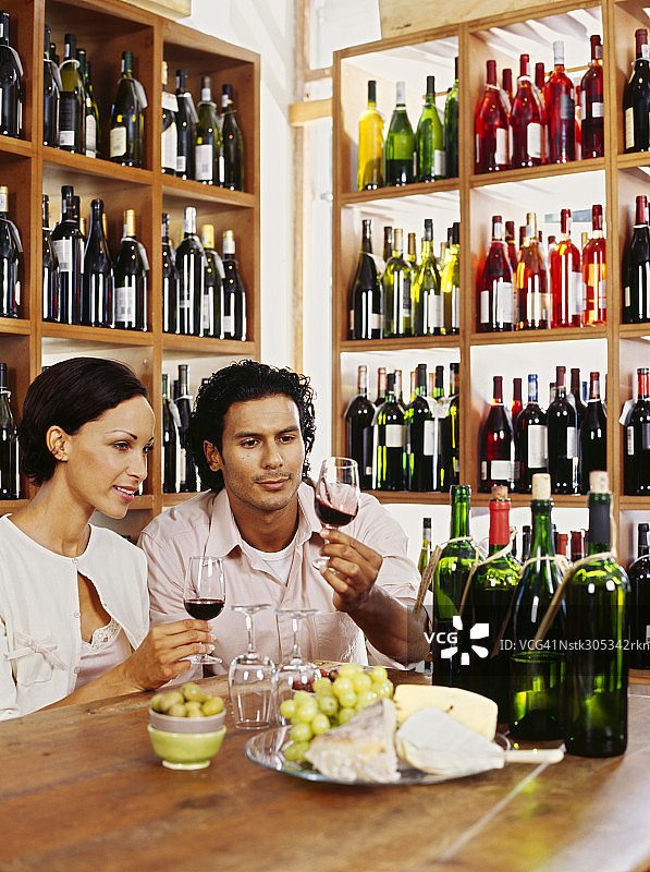 年轻夫妇在酒品店手持红酒杯图片素材