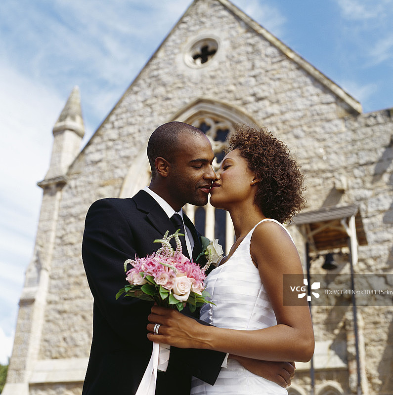 新婚夫妇在教堂外接吻的侧面照图片素材