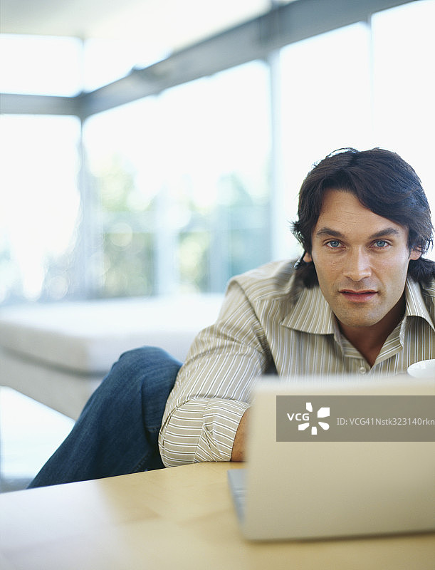 一名中年男子坐在笔记本电脑前的肖像图片素材
