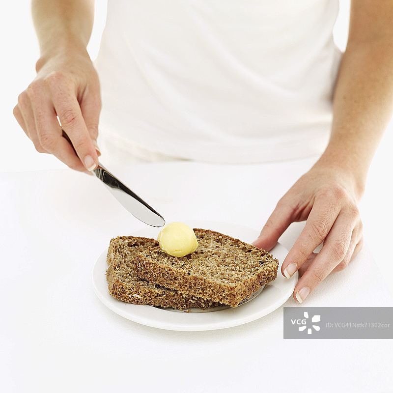 女人在面包片上抹黄油图片素材