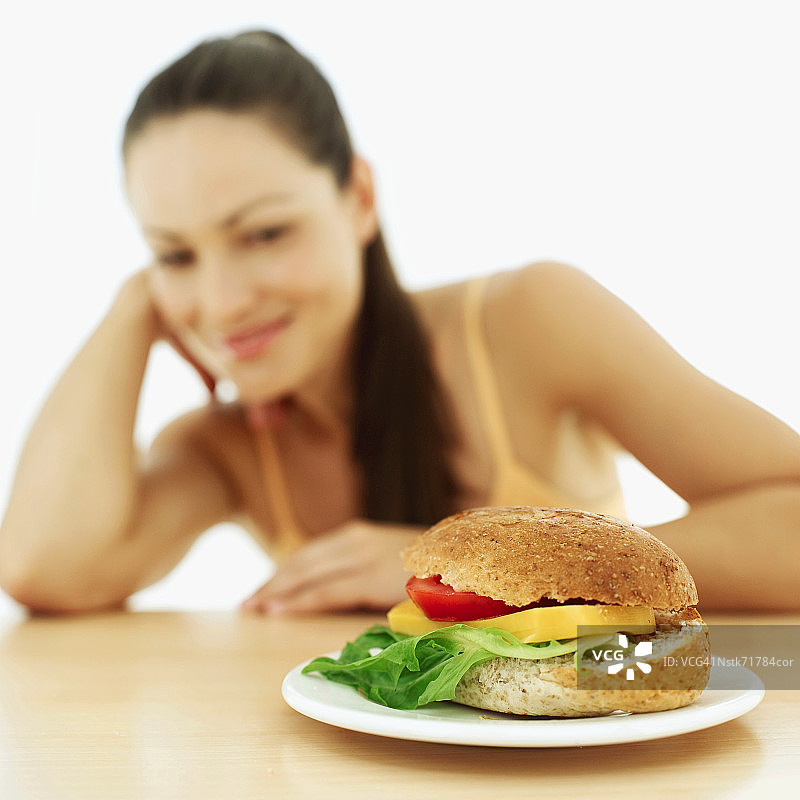 女人看着盘子里的汉堡（模糊）图片素材