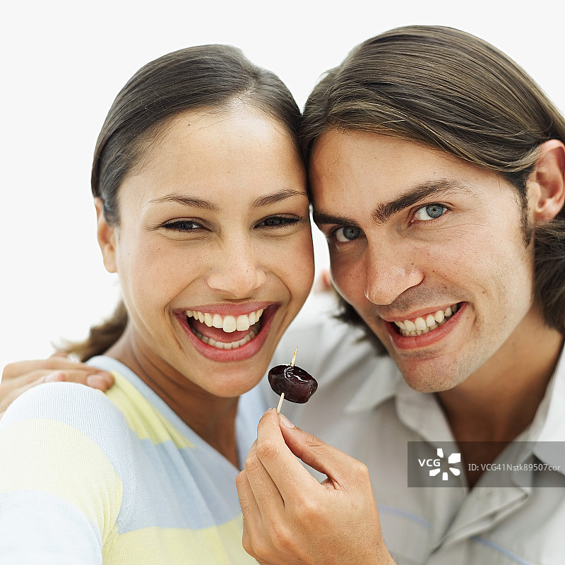 男人和女人站在一起，拿着鸡尾酒签上的枣子的特写图片素材