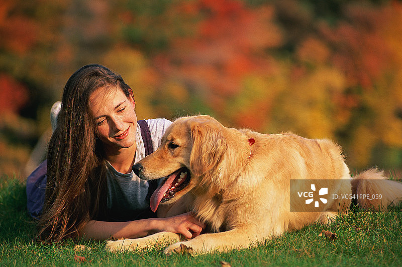 女孩躺在草地上，旁边有狗图片素材