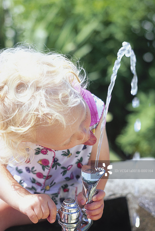 女孩在喷泉旁饮水图片素材
