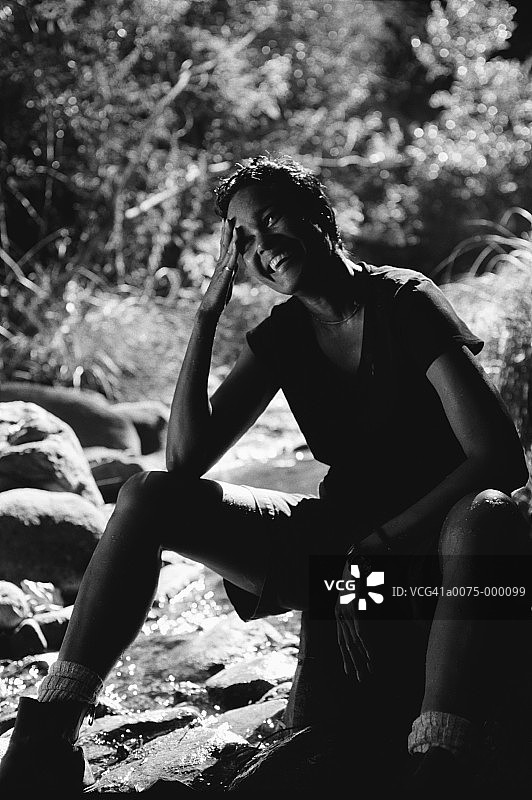 女人坐在河中的岩石上图片素材