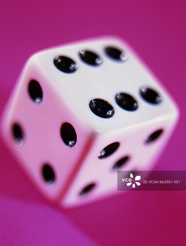 粉色背景上的骰子特写，显示点数为六图片素材