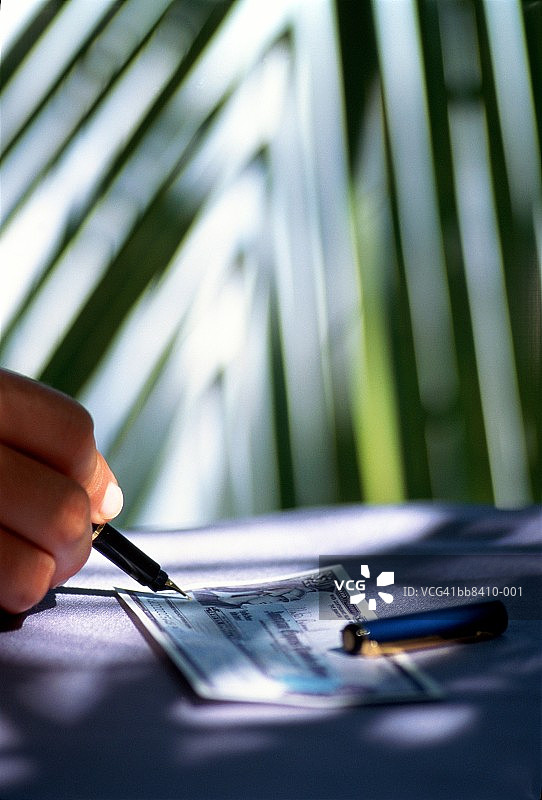手签旅行支票，背景是棕榈树，特写图片素材