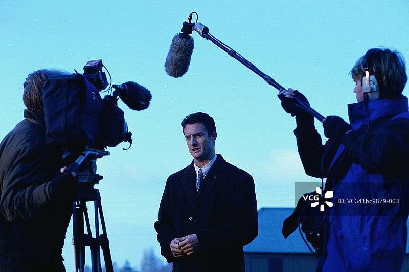 电视记者在黄昏时分的户外对着镜头讲话图片素材