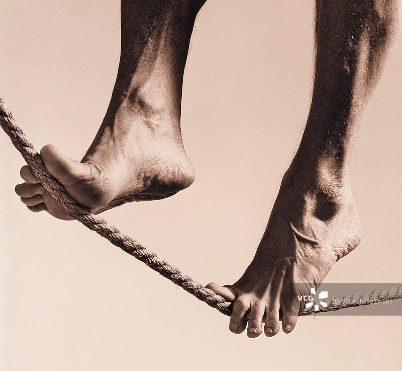 赤脚男子走在钢丝上，低角度拍摄（黑白照片）图片素材