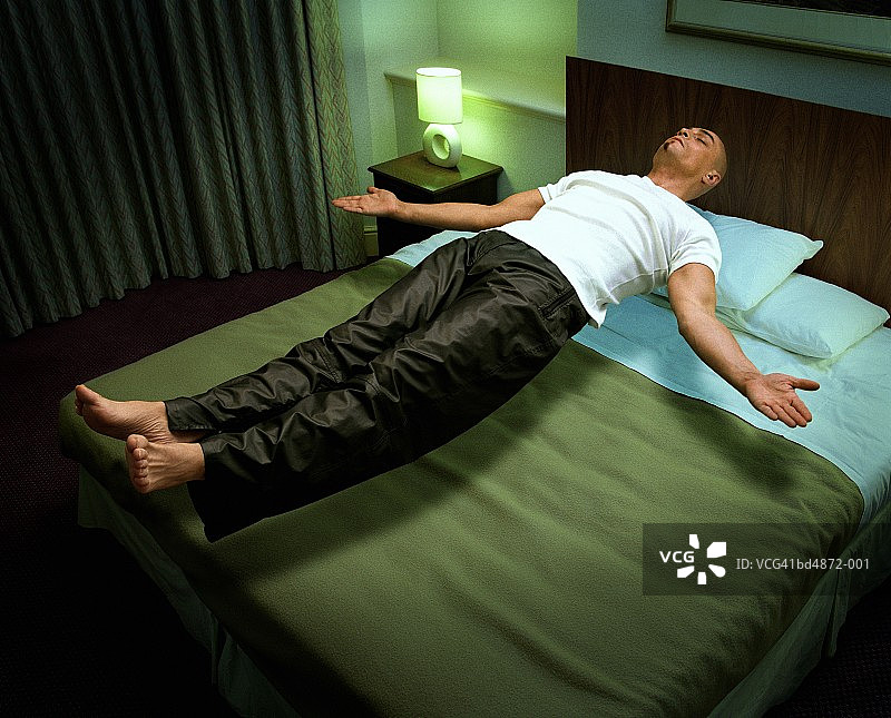 漂浮在床上的年轻男人（数字合成）图片素材