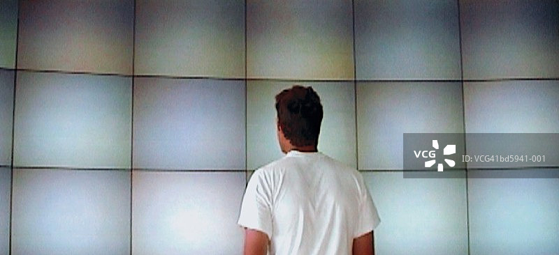 男人看着监视器墙，后视图（视频截图）图片素材