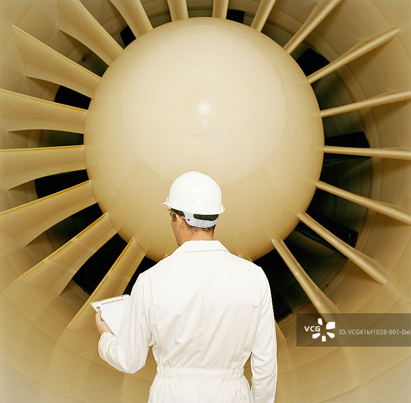 在风洞中戴着安全帽和工作服，手拿写字板的男人图片素材