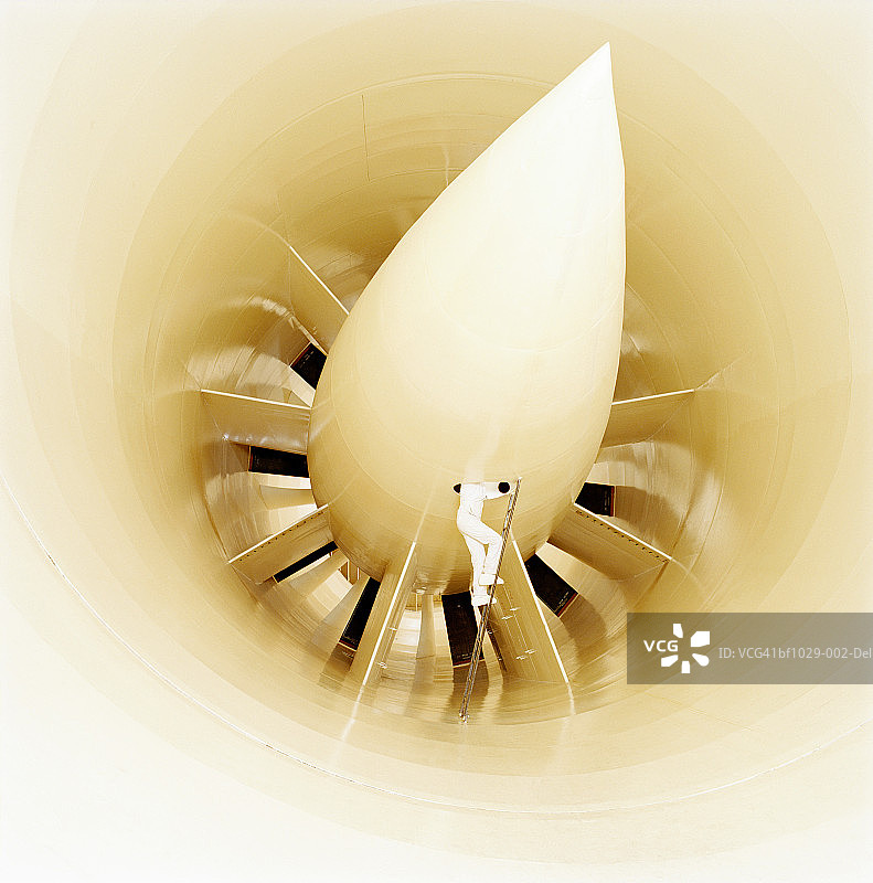 身穿工作服的男人在梯子上检查风洞，低角度拍摄图片素材