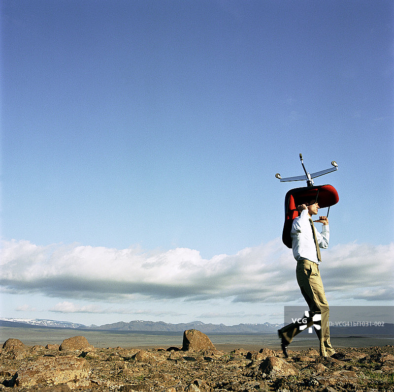 年轻男子在户外头顶着办公椅图片素材