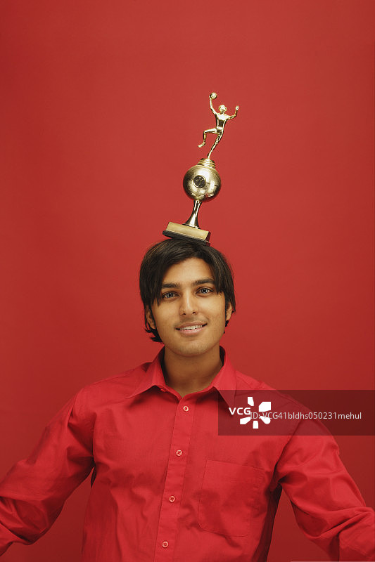 年轻男子头顶奖杯的肖像图片素材