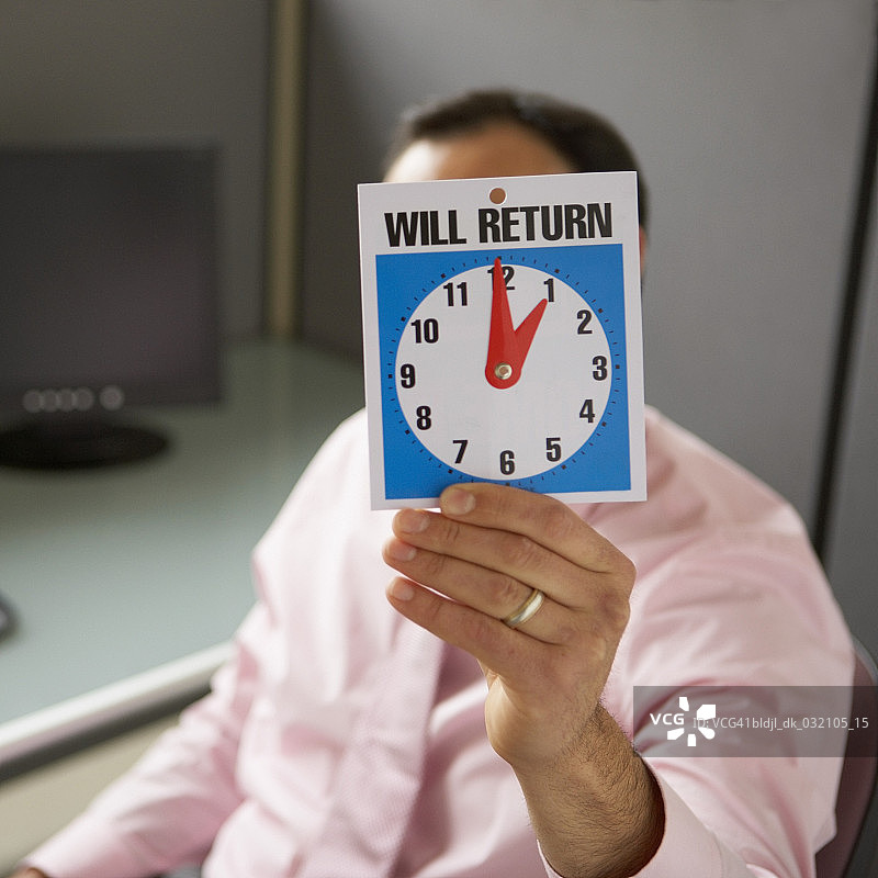 手持“即将归来”标志的商人图片素材