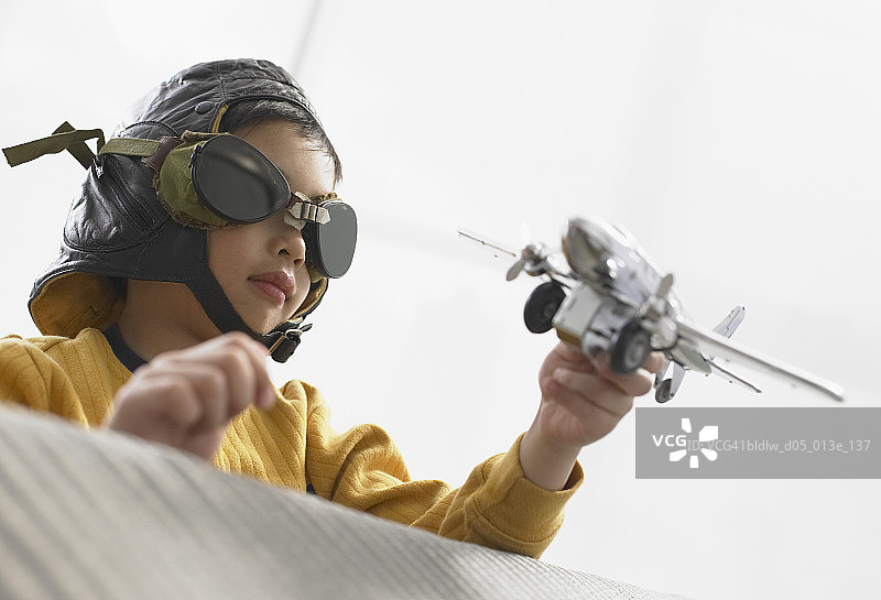 仰视角度拍摄的拿着飞机模型的男孩图片素材